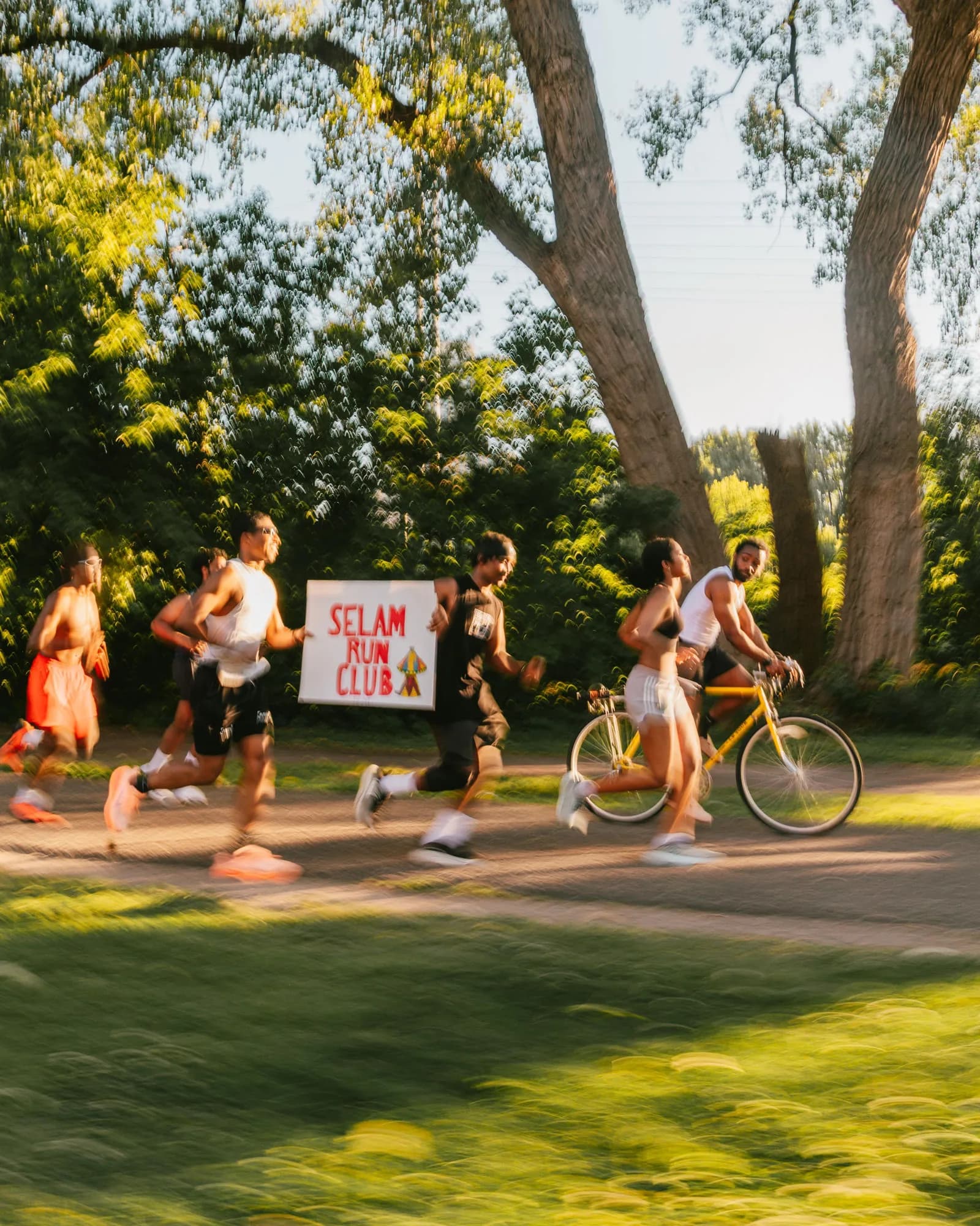 Selam Run Club members running through a park holding a hand-painted club sign